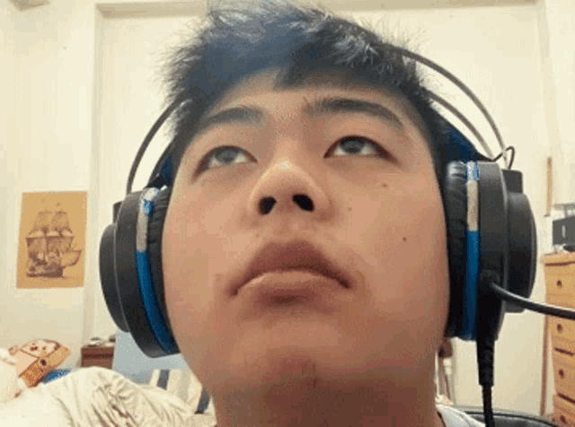 a young man wearing headphones looks up at the camera