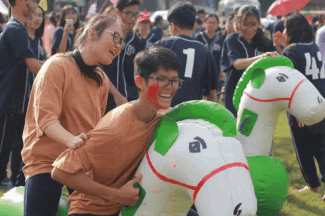 a boy wearing a number 1 jersey is being pushed by a girl