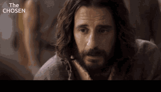 a man with long hair and a beard looks at the camera with the words the chosen above him