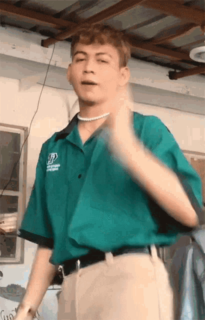a young man wearing a green shirt with the letter d on the front