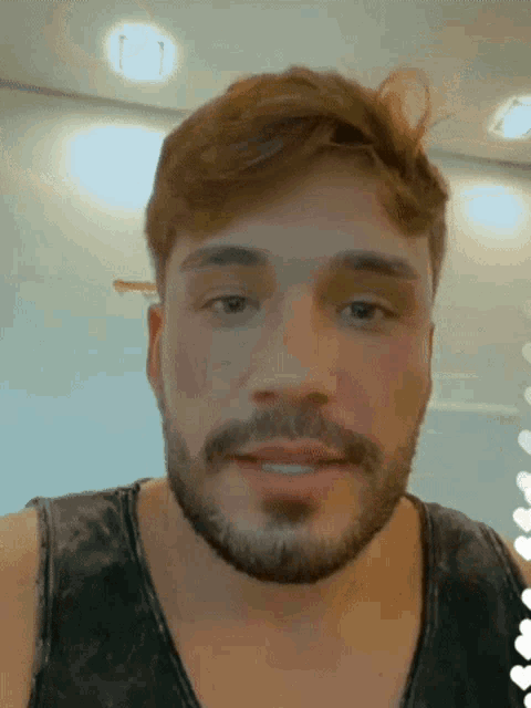 a man with a beard is wearing a tank top and smiling
