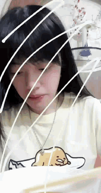 a girl wearing a t-shirt with a picture of a cat on it is looking at something .
