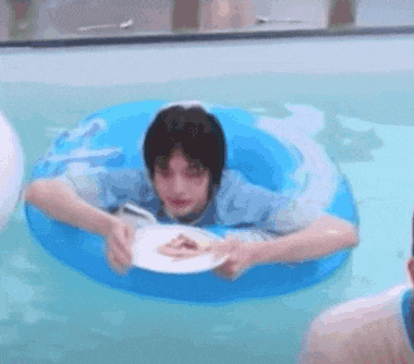 a man is floating in a swimming pool eating a pizza .