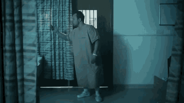 a man in a hospital gown is standing in the doorway