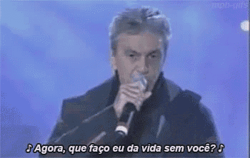 a man is singing into a microphone with the words `` agora , que faço eu da vida sem você ? ''
