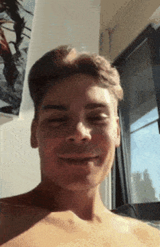 a young man without a shirt is smiling for the camera .