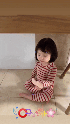 a little girl is sitting on the floor under a table with the letters o and m visible