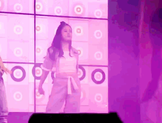 a girl is dancing in front of a pink wall