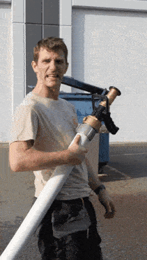 a man holding a large white hose with a brass fitting