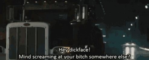 a man is walking down a street with a truck behind him and says hey dickface mind screaming at your bitch somewhere else