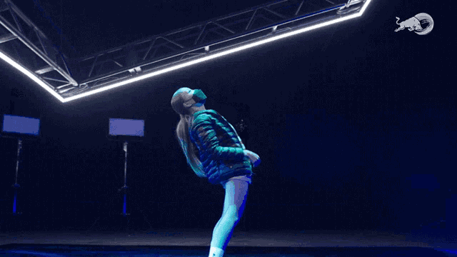 a woman is doing a handstand in a dark room with a red bull logo on the ceiling