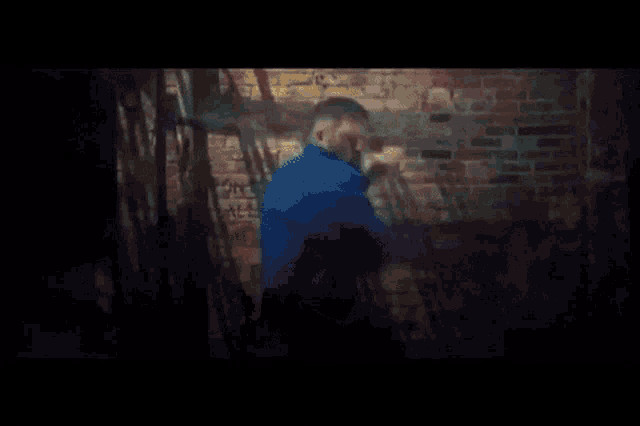 a man standing in front of a brick wall