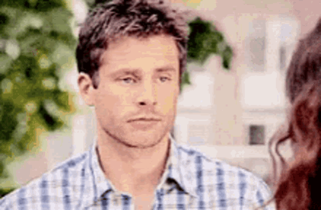 a man in a plaid shirt is looking at a woman in a pink shirt .