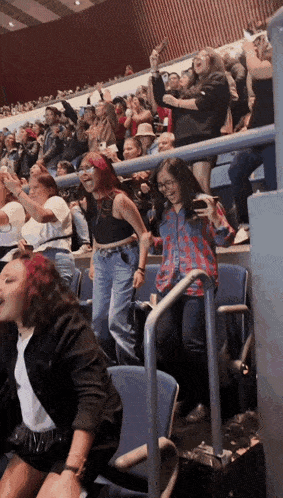 a group of people are sitting in a stadium and one of them is taking a picture of herself