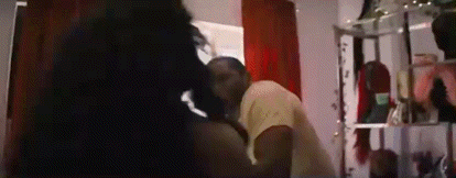 a man and woman are kissing in a room .