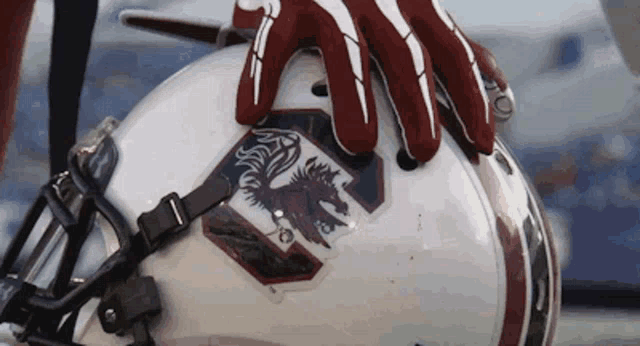 a close up of a person holding a football helmet with gloves on .