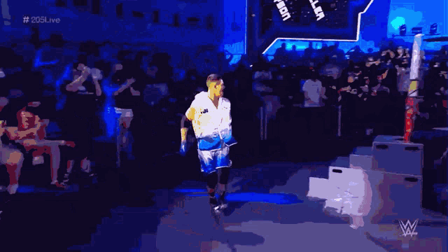 a man in a white shirt with the word johnson on it walks into a wrestling ring