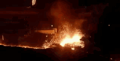 a large fire is coming out of a building at night