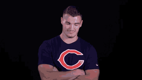 a man wearing a chicago bears t-shirt stands with his arms crossed