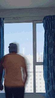 a man standing in front of a window looking out