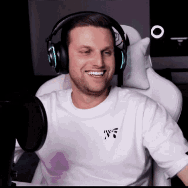 a man wearing headphones is smiling in front of a microphone while wearing a white shirt