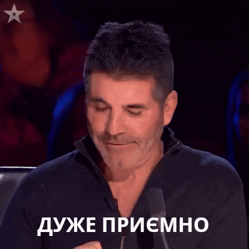 a man is sitting in front of a microphone with a star in the background and a foreign language on his face .