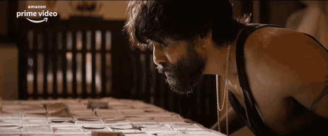 a man with a beard is looking at a pile of cards on a table that says prime video