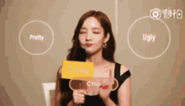 a woman is holding a microphone with the words pretty and ugly on it