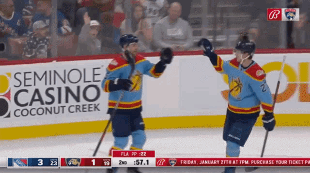 two hockey players are celebrating a goal in front of a seminole casino advertisement