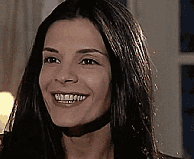 a close up of a woman 's face with long hair smiling