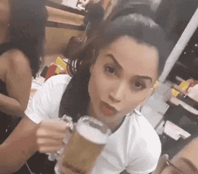 a woman is holding a glass of beer and making a face .