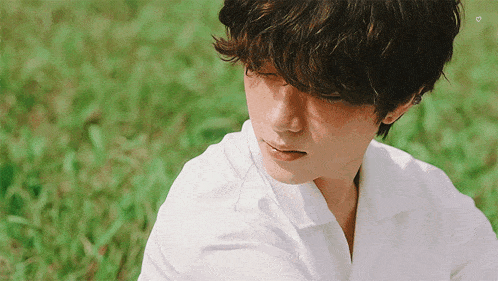 a man in a white shirt is sitting in the grass