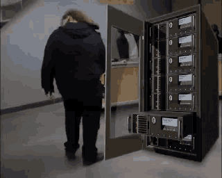 a man in a black jacket is walking towards a server with the number 0 on it