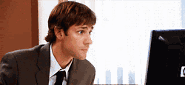 a man in a suit and tie is looking at a hp monitor