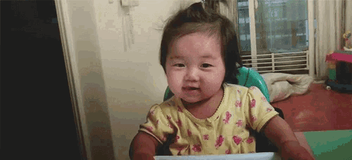a baby girl is sitting in a high chair and making a face .
