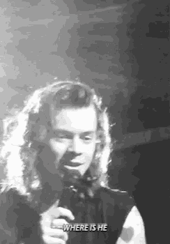 a black and white photo of a man singing into a microphone on stage .