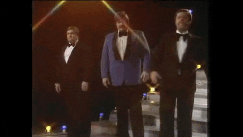 three men in tuxedos and bow ties are standing on a stage .
