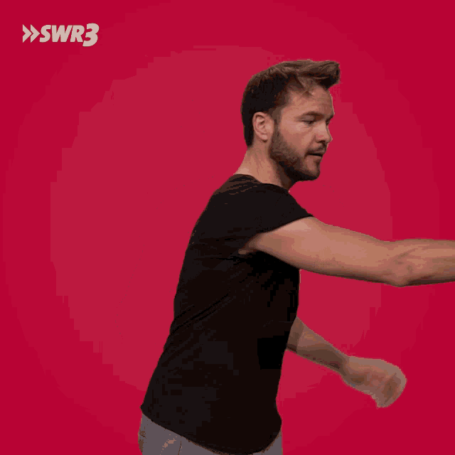 a man in a black shirt is holding a guitar in front of a red background with swr3 in white letters