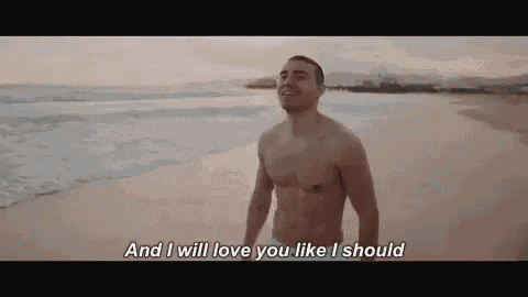 a shirtless man is standing on a beach talking to someone .