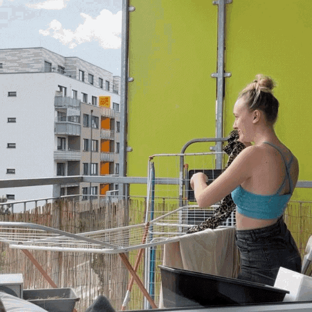 a woman in a blue crop top is standing on a balcony