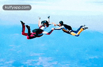 a group of people are flying through the air and one of them is holding another person 's hand .
