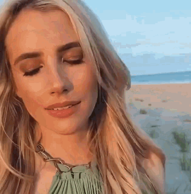a close up of a woman 's face with her eyes closed on the beach .
