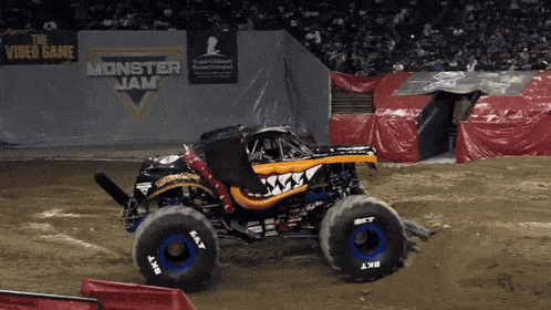 a monster jam truck is driving on a dirt road