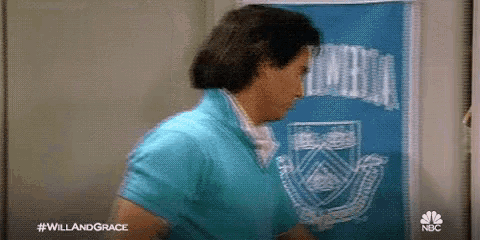 a man in a blue shirt is standing in front of a blue board with a drawing of a crest on it .