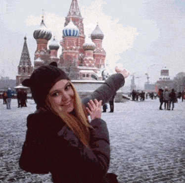 a woman stands in front of a snowy russian building