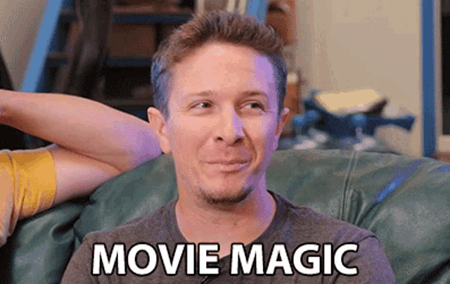 a man is sitting on a couch with the words movie magic written on his chest