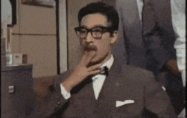 a man in a suit and tie with glasses and a mustache