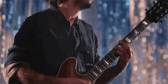 a man is playing a guitar with a blue background