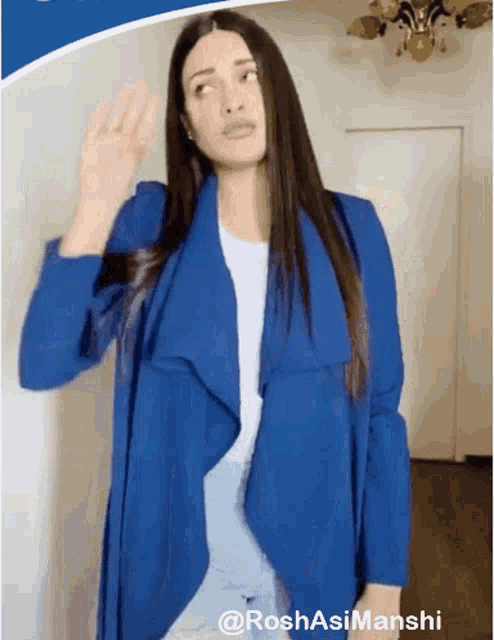 a woman wearing a blue jacket and a white shirt is waving her hand