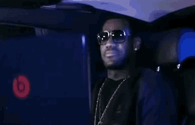 a man wearing sunglasses is sitting in the back of a car .